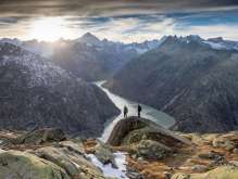 Two hikers on the trail in the Grimsel region. They are hiking with a breathtaking view of a reservoir in the Grimsel region.