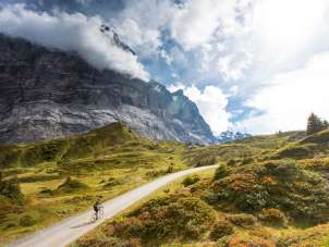 Cyclistes sur la route menant à la Grosse Scheidegg, avec vue sur le Wetterhorn et le paysage alpin.