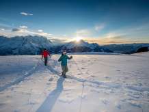 Au coucher du soleil, avec un panorama montagneux impressionnant en toile de fond : deux randonneurs en raquettes sur le Hasliberg