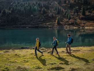 Le groupe longe les rives du lac, dont l'eau scintille d'un turquoise intense. La végétation automnale et l'ombre des arbres créent un décor plein de charme.