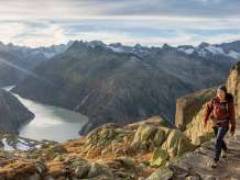 Deux randonneurs en route dans le massif du Grimsel. Ils marchent devant un panorama unique sur un lac de barrage du massif du Grimsel.