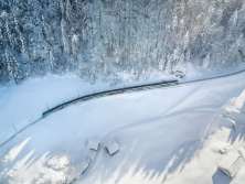 Through the snow-covered winter landscape: The Luzern-Interlaken Express panoramic train operated by Zentralbahn traveling through the Brünig-Hasliberg region.