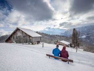 Winter Hike on Hasliberg: Two hikers are sitting on a small bench, taking a break.