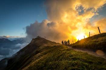 A cyclist riding along the Hasliberg. In the background, a beautiful sunset stretches out between the clouds.