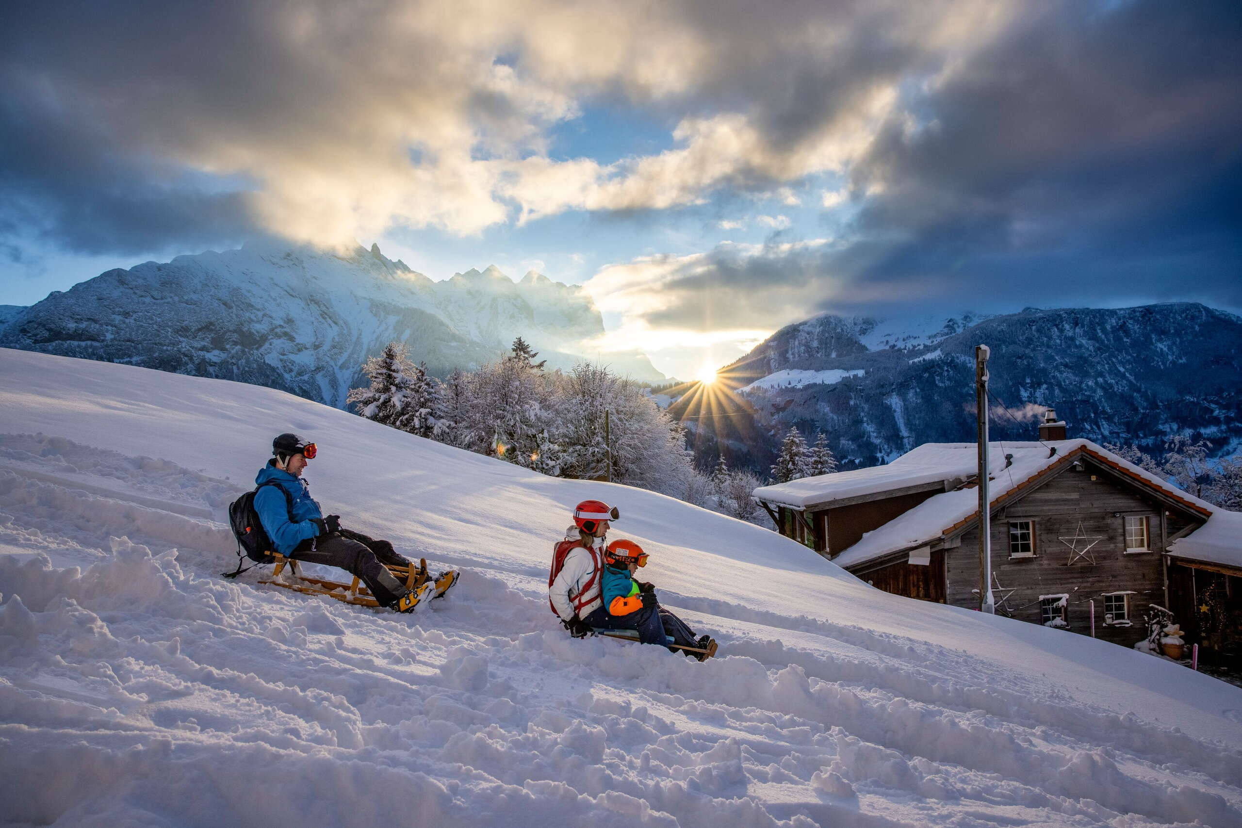 Au coucher du soleil : une jeune famille fait de la luge sur le Hasliberg.