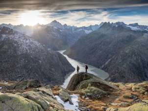 Two hikers on the trail in the Grimsel region. They are hiking with a breathtaking view of a reservoir in the Grimsel region.