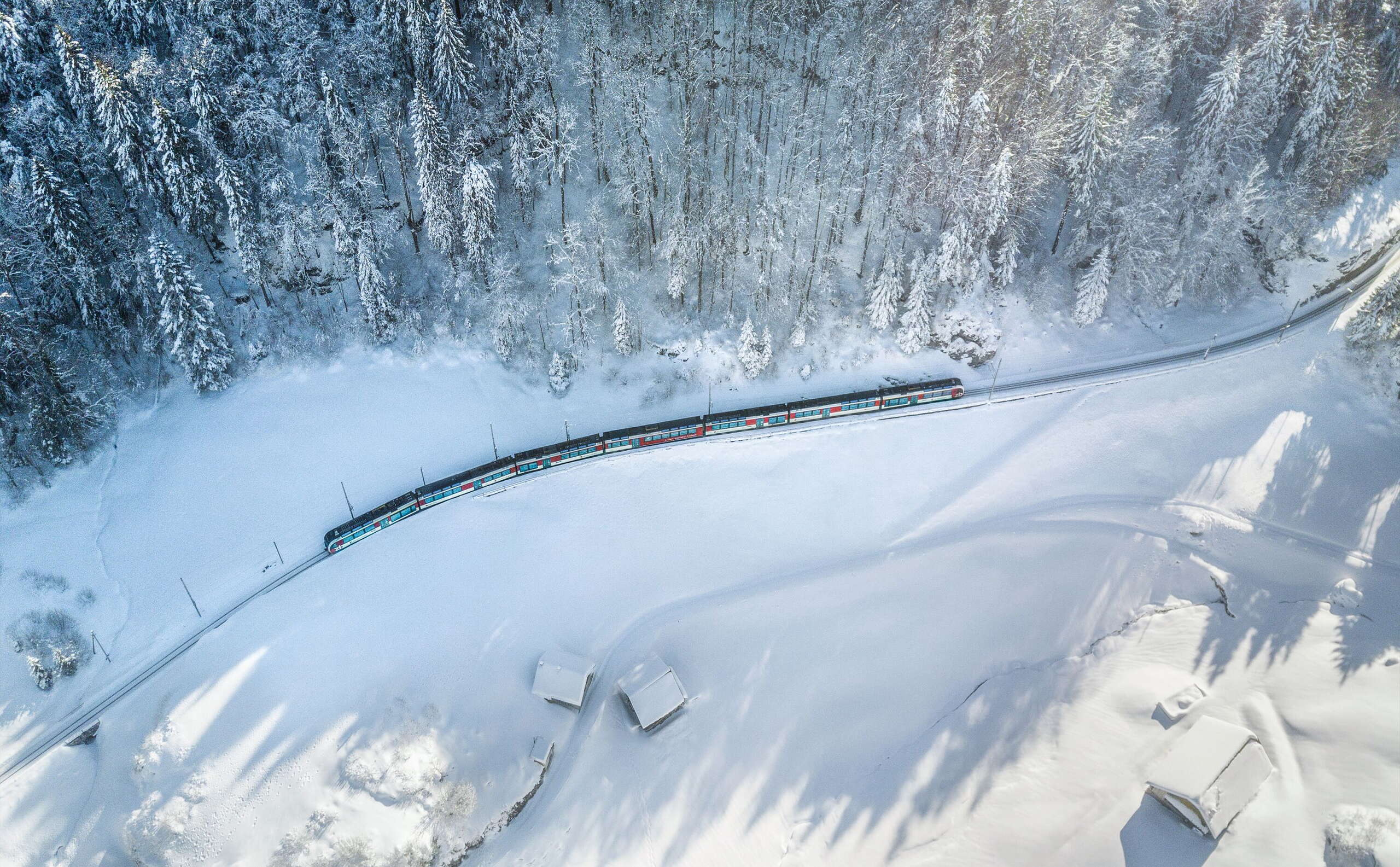 A travers le paysage hivernal enneigé : le train panoramique Lucerne-Interlaken Express du Zentralbahn en route dans la région de Brünig-Hasliberg.