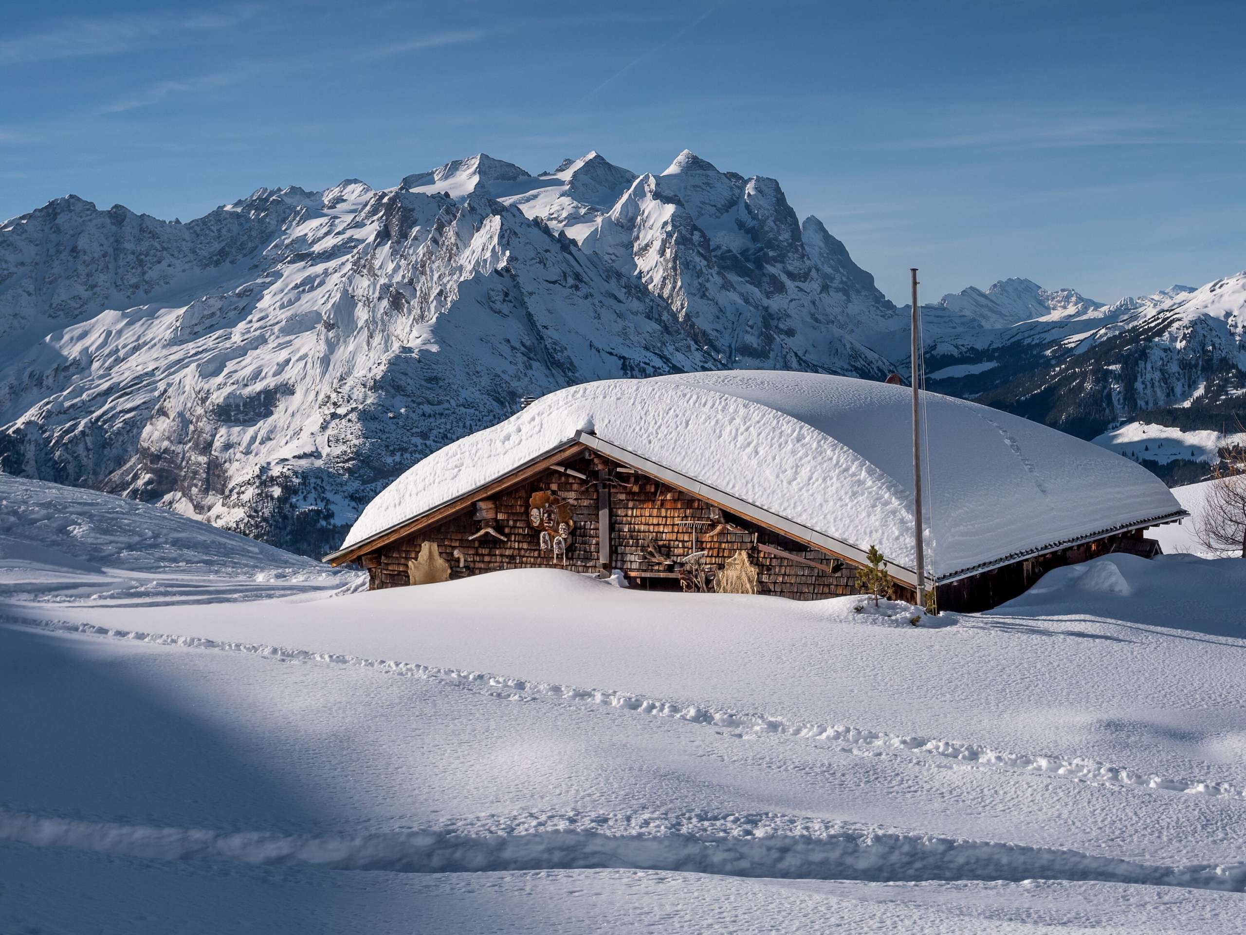 Winter landscape on the Hasliberg. In the foreground a snow-covered hut, in the background the alpine peaks of the Haslital.