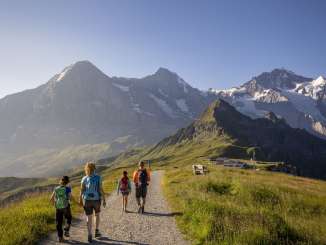 Eine Familie auf dem Royal Walk. Wanderung mit Aussicht auf den Männlichen und das Dreigestirn Eiger, Mönch und Jungfrau.
