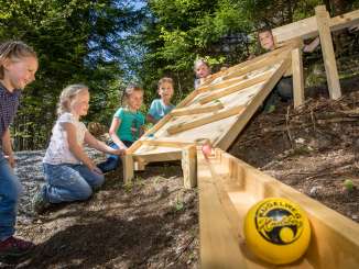 The children are playing on the permanent wooden marble runs along the Kugelweg in Hasliberg.