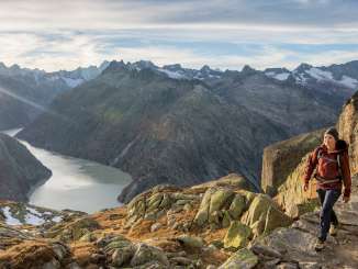 Two hikers on the trail in the Grimsel region. They are hiking with a breathtaking view of a reservoir in the Grimsel region.