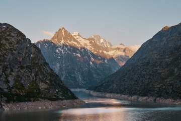 Aussicht über den Grimselsee mit Bergspitzen im Abendrot.
