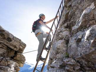 A woman on the Tälli via ferrata in the Haslital. Along the way, she climbs a ladder. The entire via ferrata offers a breathtaking view.