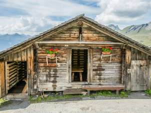 A small cabin on the Schwarzwaldalp with geraniums along the facade. The door is open.