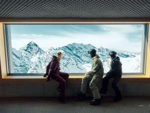 Trois personnes profitent de la vue panoramique depuis la station de Birg. Les « Piz Gloria Frames » offrent une vue imprenable sur les montagnes enneigées.