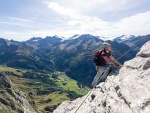 Une femme sur la via ferrata du Tälli, dans le Haslital. Bien assurée, elle progresse le long de la paroi rocheuse. Tout au long de la via ferrata, on peut profiter d'une vue imprenable.