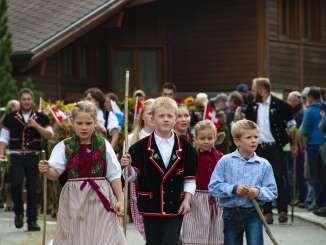 Die Kinder laufen beim Alpabzug Gental in traditionellen Kleidern dem Umzug vorab.