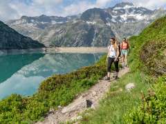 Les randonneurs font le tour du lac de Gelmer, dans le Haslital. Le sentier longe le lac en passant entre de petits buissons.