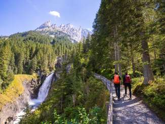 The river has shaped the Rosenlaui Glacier Gorge over the centuries. The trail leads along the rock face above the river and into the gorge. The waterfall can be seen through the fir forest. The mountain panorama in the background rises majestically. Two Wa