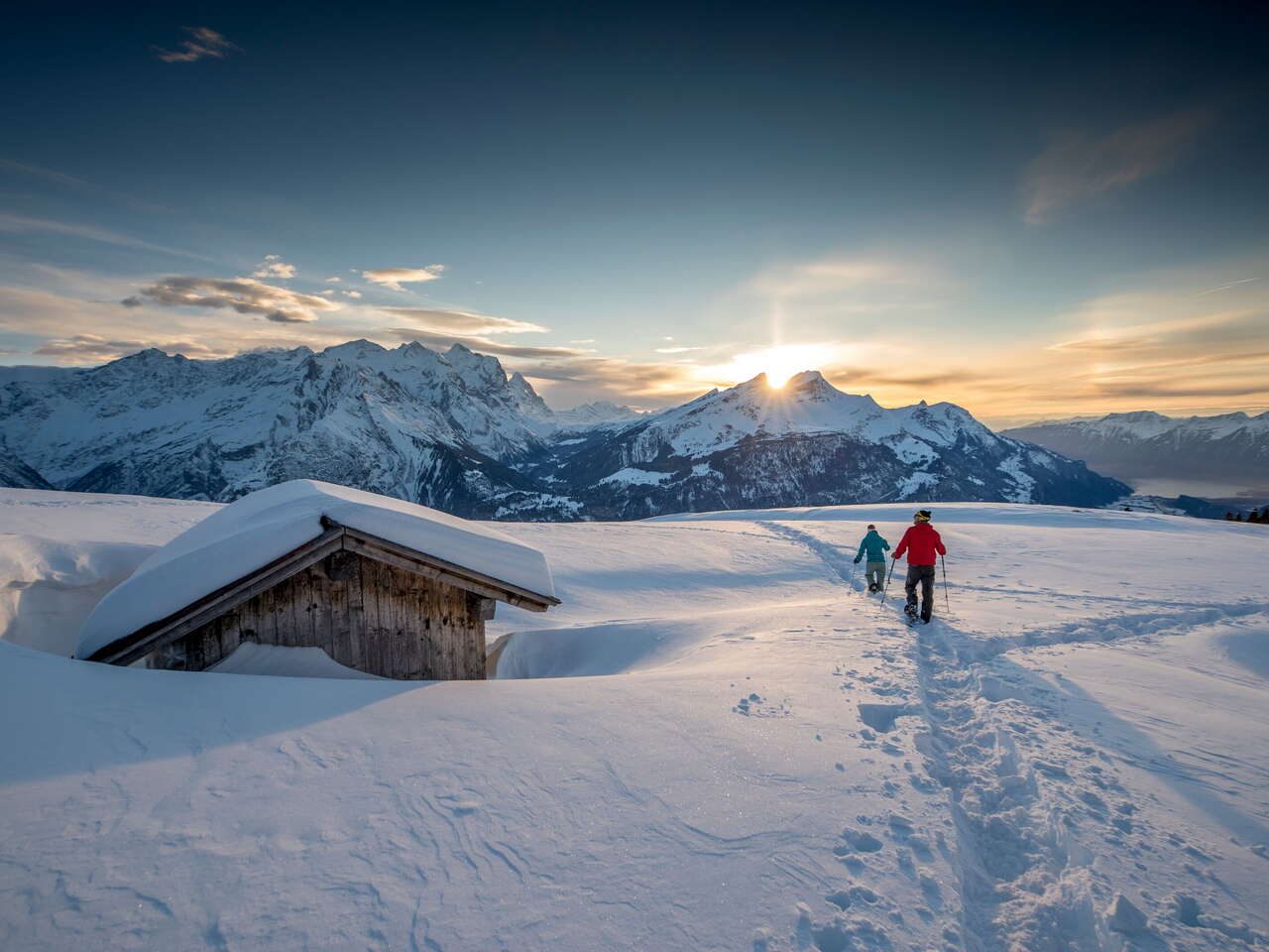 Im Sonnenuntergang - und vor eindrücklicher Bergkulisse: Zwei Schneeschuhläufer*innen unterwegs am Hasliberg