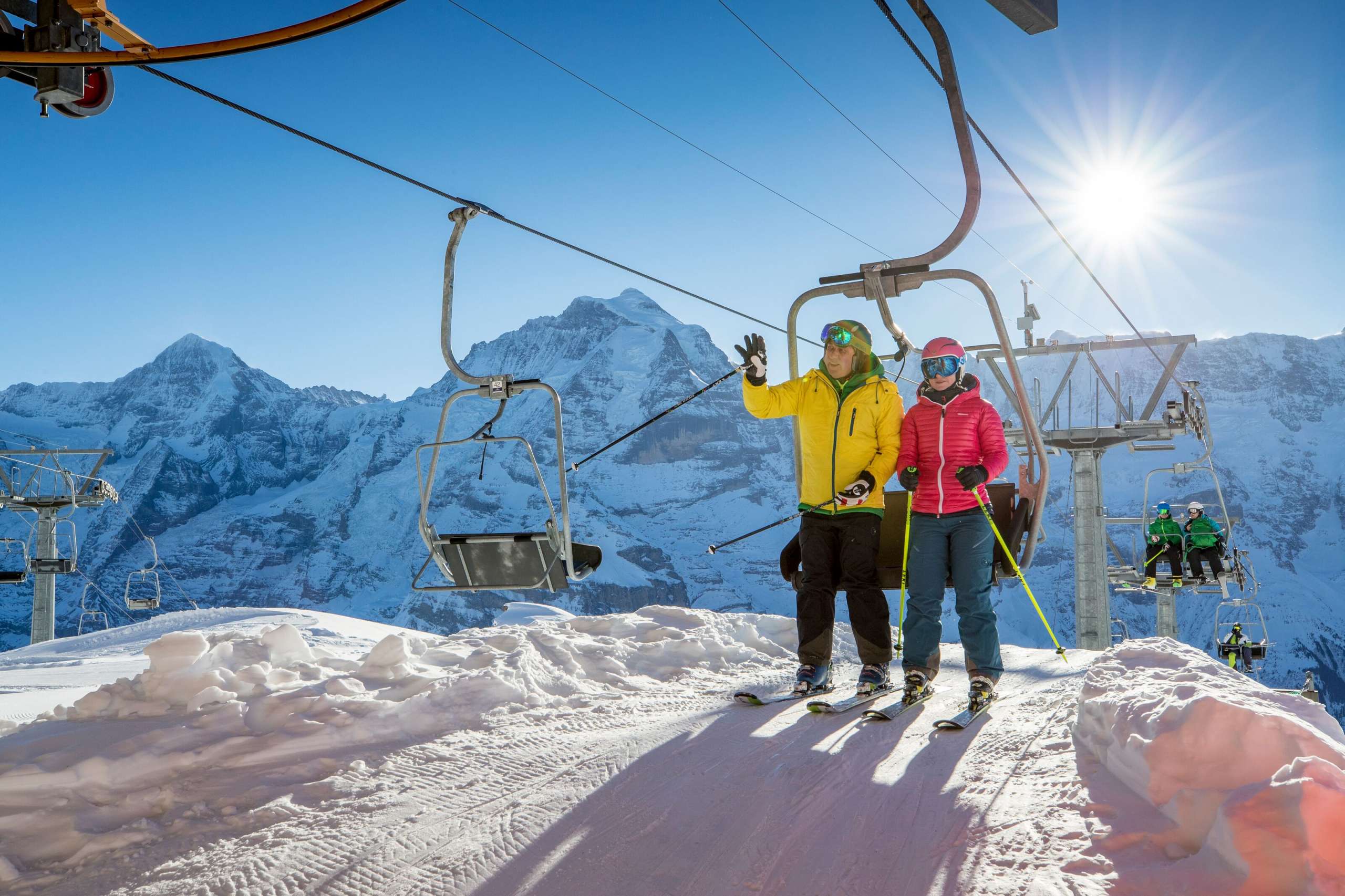 Skifahren Skigebiet Mürren-Schilthorn Skifahrer stehen vom Sessellift auf im Skigebiet Mürren-Schilthorn. Das Dreigestirn Eiger, Mönch und Jungfrau ist aus der Ferne zu sehen.