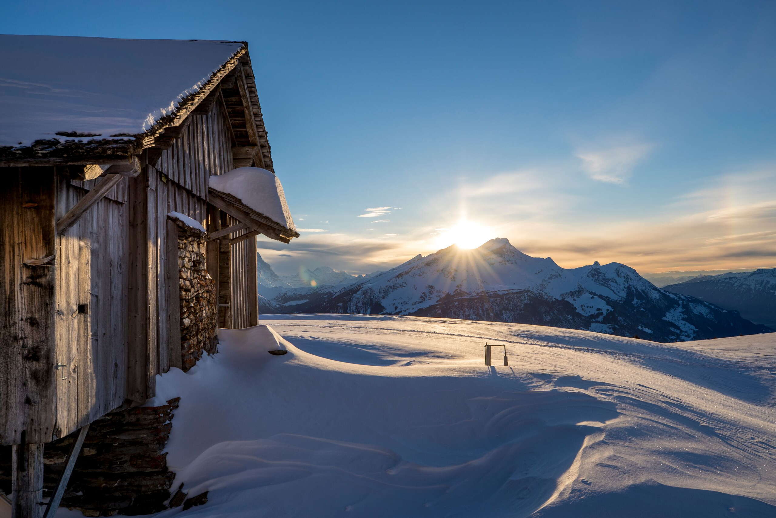 Au coucher du soleil - et dans un décor de montagne impressionnant : Deux raquetteurs* en route sur le Hasliberg