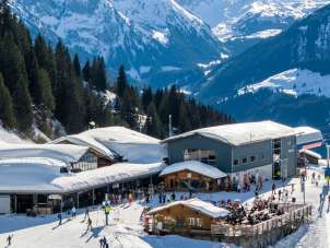 Die Station Mägisalp liegt eingebettet in der winterlichen Berglandschaft auf dem Hasliberg. Rund um die Gebäude verlaufen präparierte Wege und Pisten. Im Hintergrund ragen markante Berggipfel der umliegenden Alpen in den Himmel.